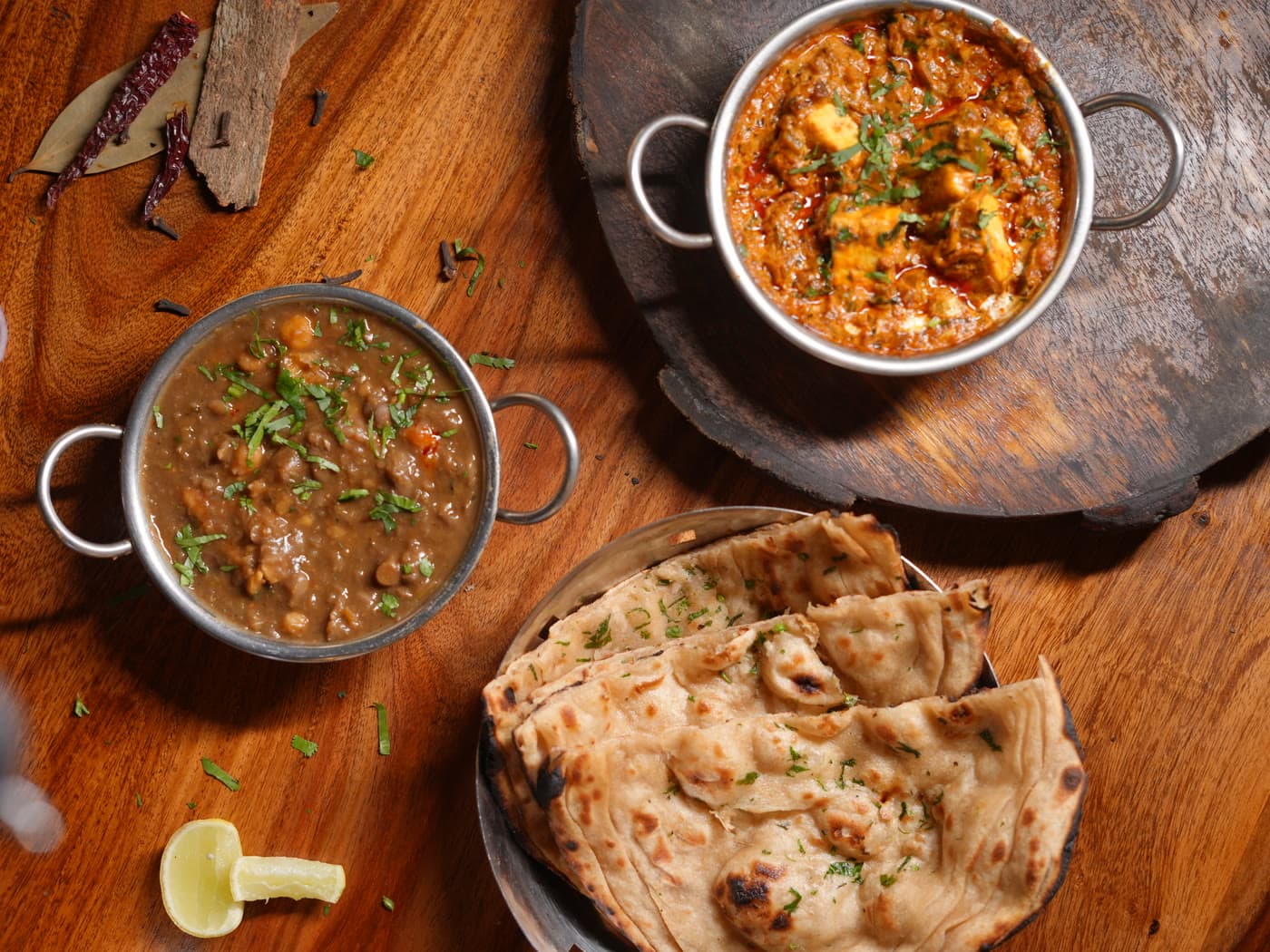 Curries and fresh tandoori roti on a wooden board
